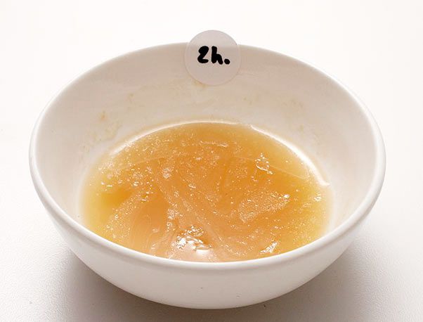 Small bowl of gelatin-flecked pork broth with a sticker that reads two hours.