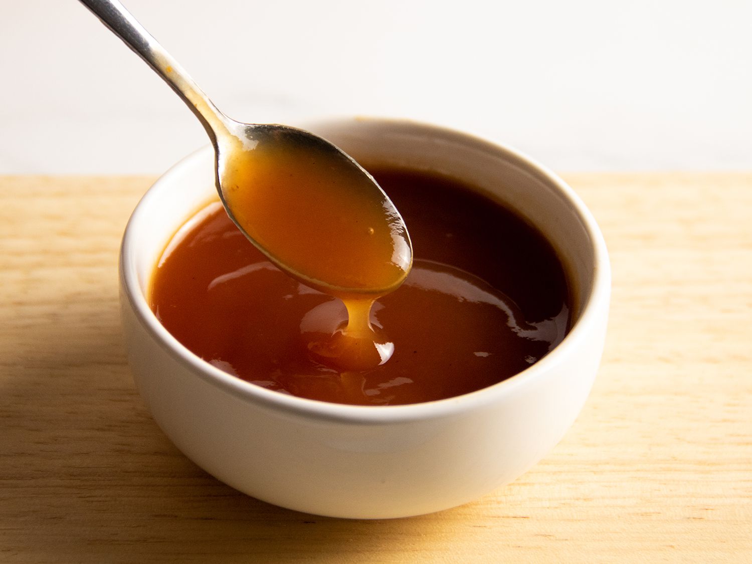 Sweet and sour sauce with a metal spoon and a white ceramic bowl.