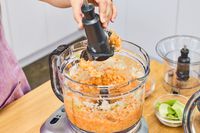 A person removes the blade from the Breville 16-Cup Sous Chef Peel & Dice Food Processor