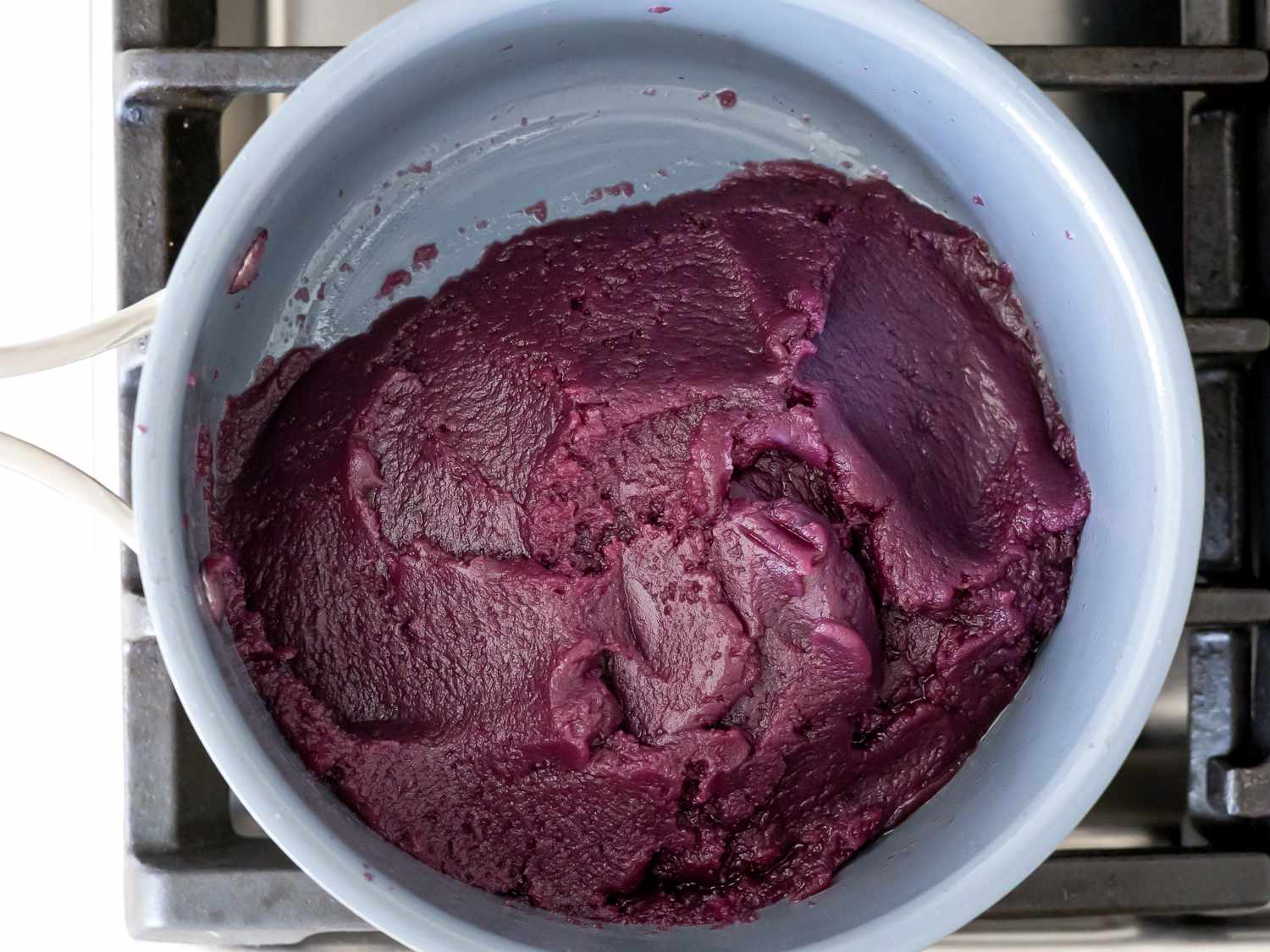 The finished ube halaya, thick enough to mound on one side of the saucepan.