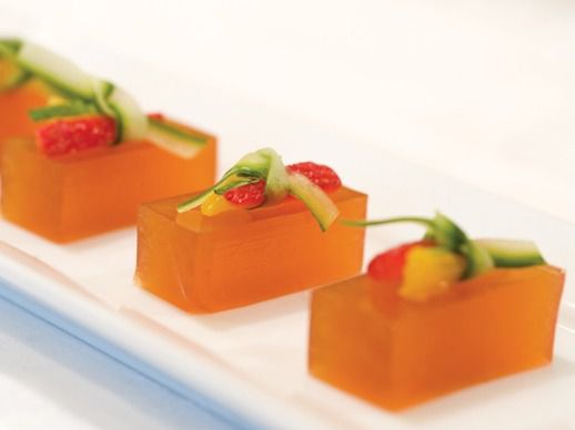 Pimms Cup Jelly Shots cut into rectangular pieces and topped with very small pieces of cucumber and strawberry.