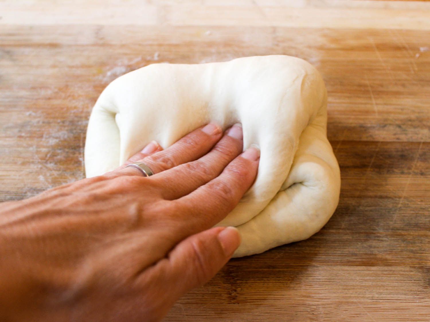 Close-up of the strudel dough being folded on a wooden work table.
