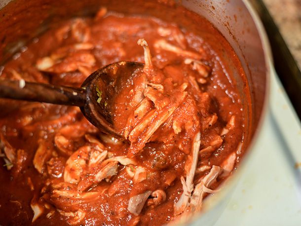 Chicken tinga is stirred in a saucepan.