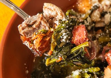 A spoonful of Italian wedding soup featuring meat greens and small pasta in a broth