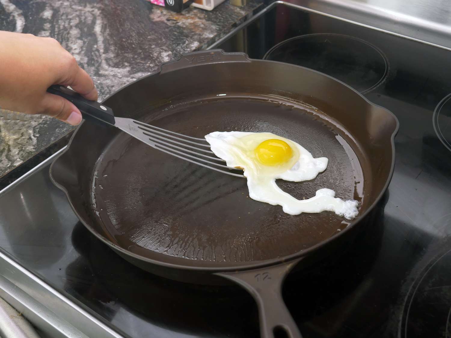 a person using a fish spatula to flip a fried egg
