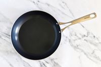 A Kyocera ceramic nonstick frying pan with a metal handle on a marble surface