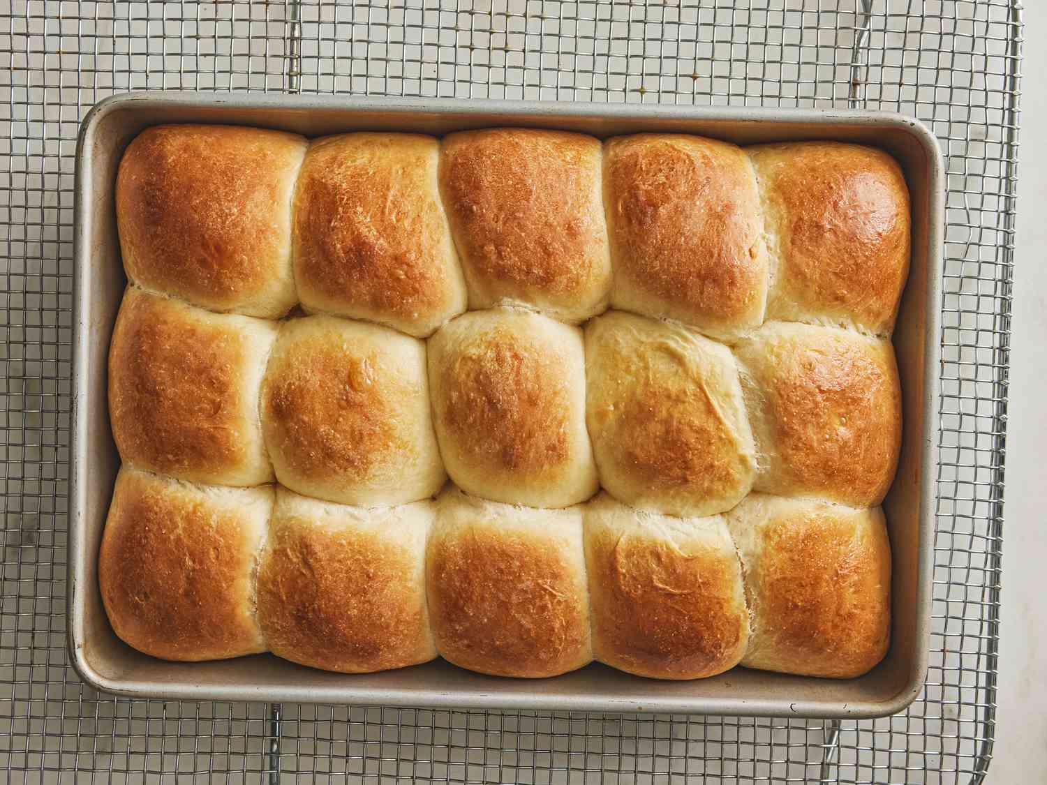 Baked parkerhouse roll in a pan on a cooling rack 