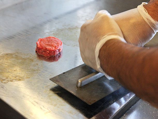 Smashing burger patty on the griddle