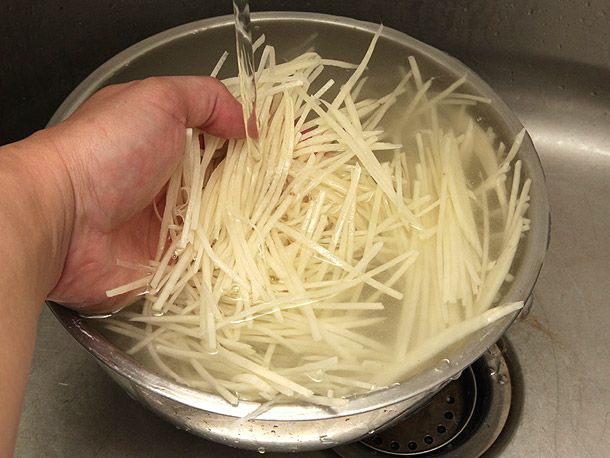 Julienned potatoes are rinsed in water.