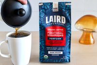 A bag of Laird Superfood organic coffee with functional mushrooms next to a cup being filled from a French press