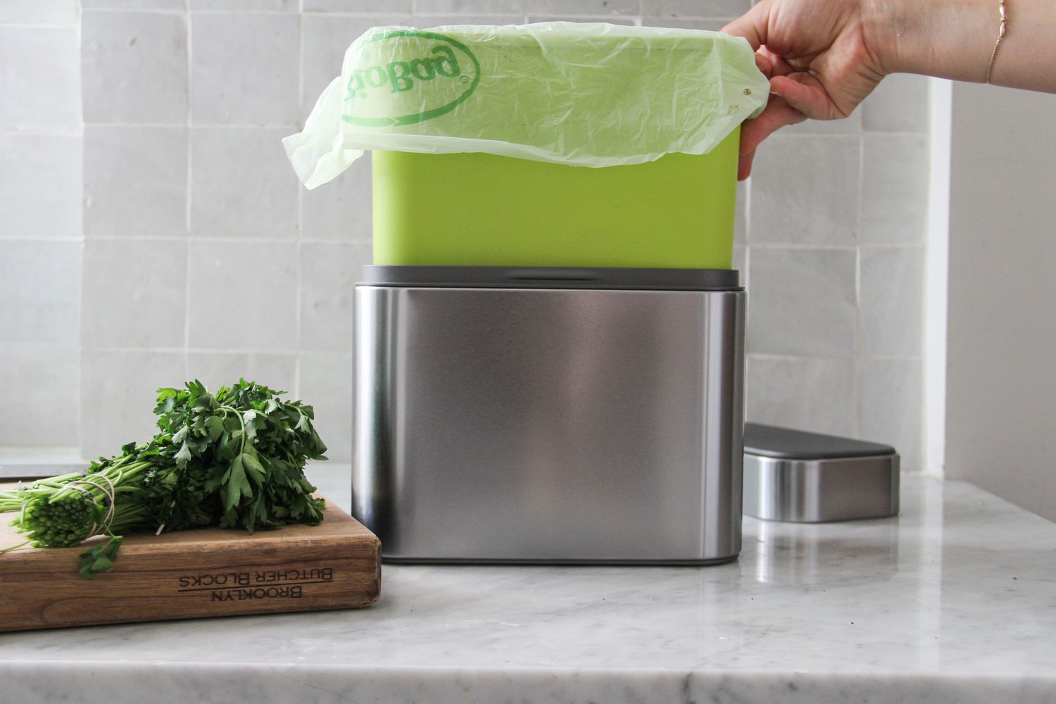 A hand lifting the interior of SimpleHuman compost caddy