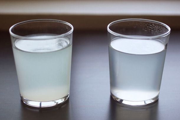 Side view of two glasses of pasta cooking water. The water on the left is cloudier.