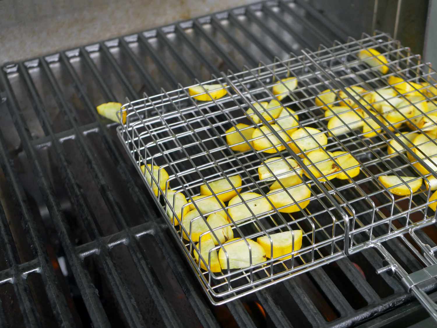 a clamping grill basket after being flipped with pieces of summer squash falling out