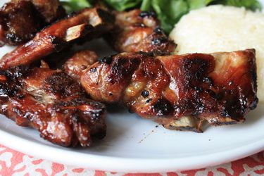 Closeup of Thai style grilled pork neck plated with rice and greens.