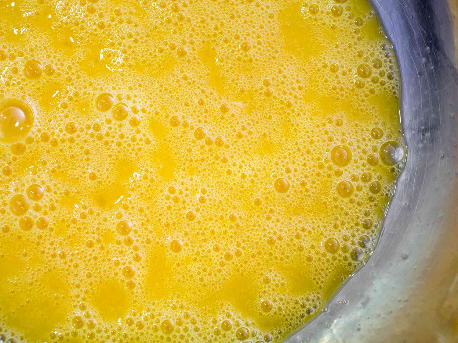 A close up of beaten eggs in a bowl.