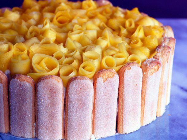 Mango Icebox Cake with ladyfingers around the sides and curls of fresh mango on top. 