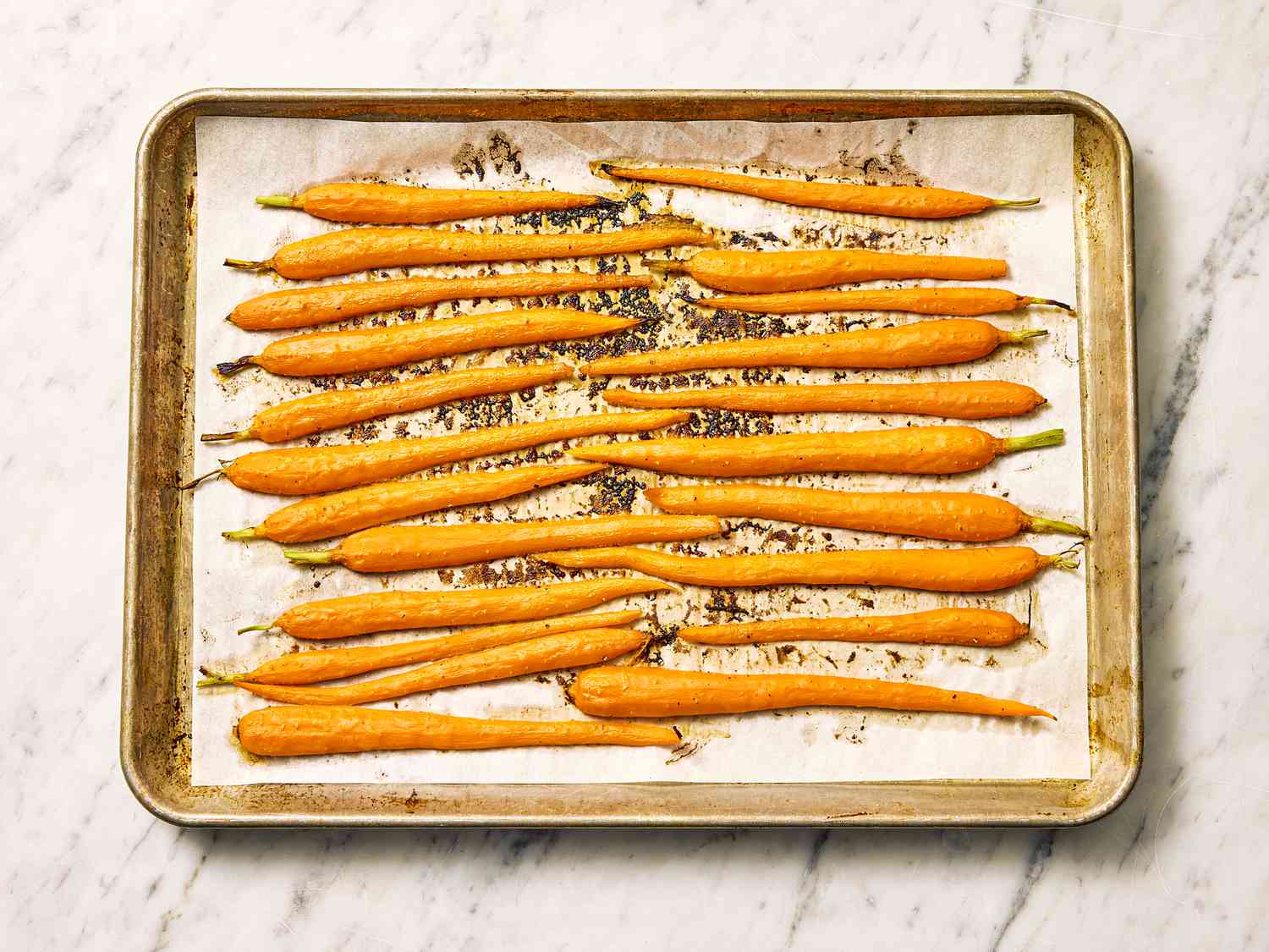 Roasted carrots arranged on parchment-lined baking tray