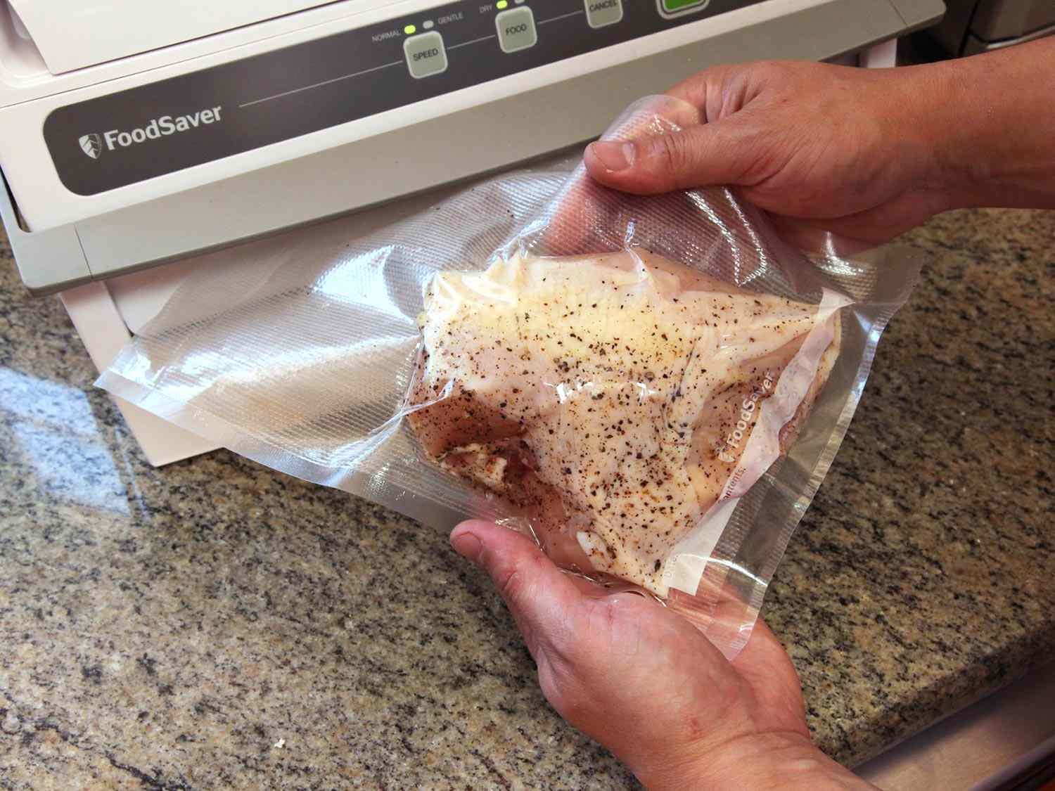 Vacuum-sealing bagged seasoned chicken breast before cooking sous vide.