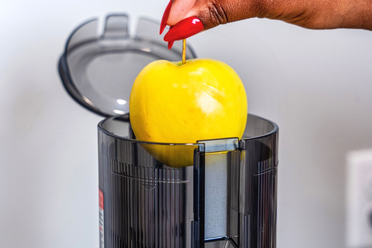 A person adds an apple to the chute of a juicer