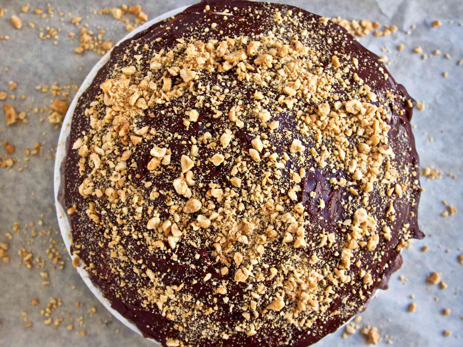 Adding another layer of chocolate caramel and chopped peanuts to the top of the Snickers pie.