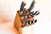 A wooden knife block containing a set of knives and kitchen shears arranged upright
