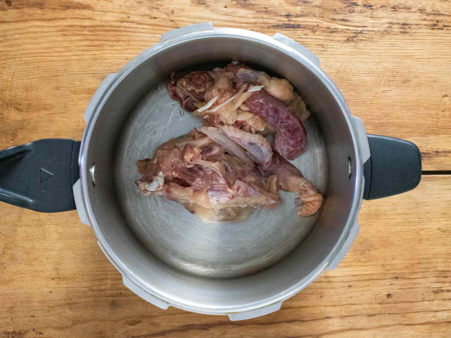 Chicken carcass, neck, and trim in a pressure cooker.