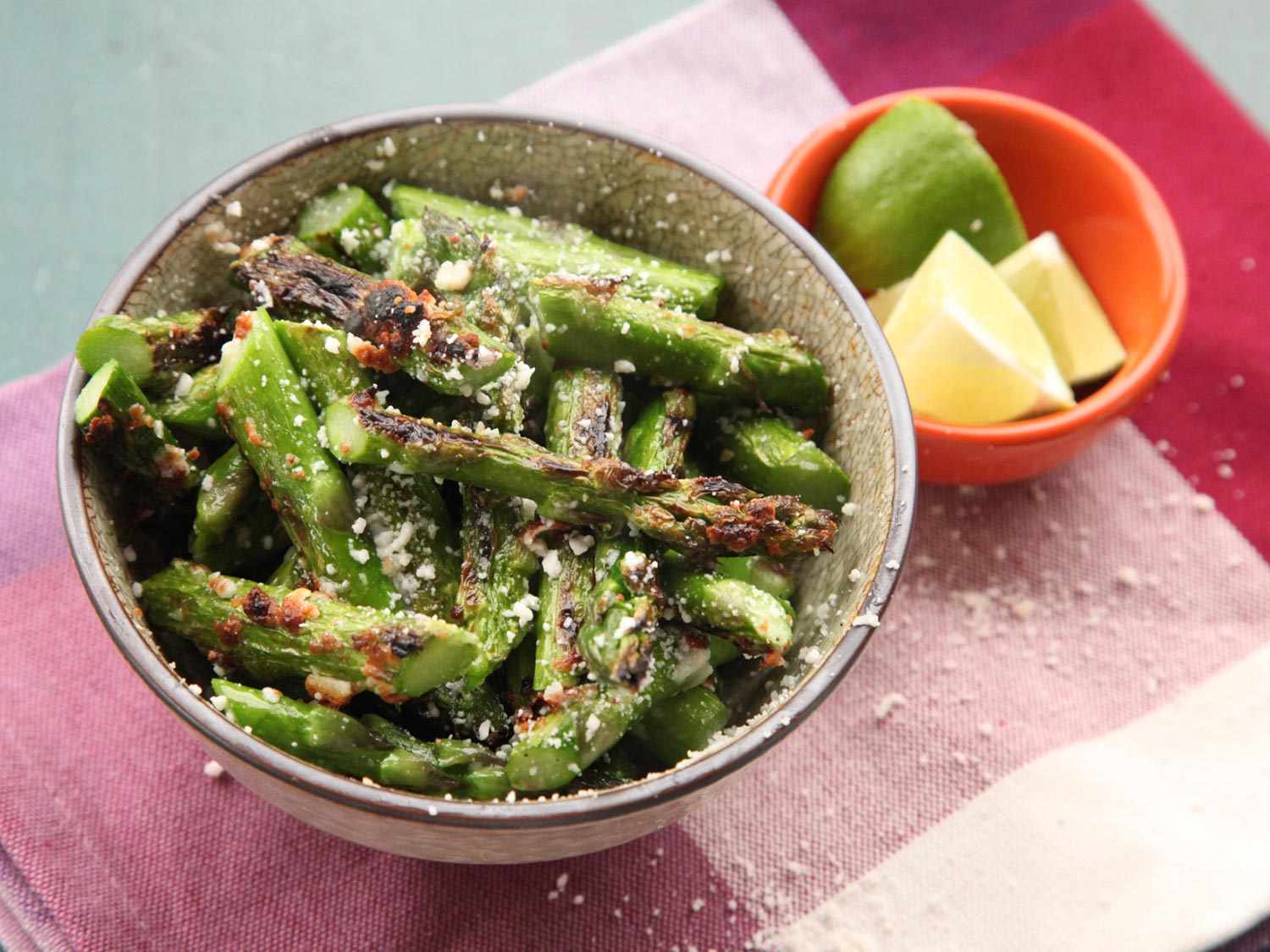 Closeup of broiled asparagus, sliced into pieces and sprinkled with cotija cheese.