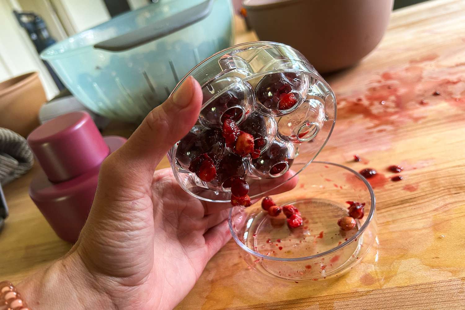 A multi-cherry pitter that still has pits clinging to the cherries.