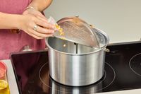 A person pours popcorn kernels into the Wabash Valley Farms Original Whirley-Pop Popcorn Popper Stainless Steel