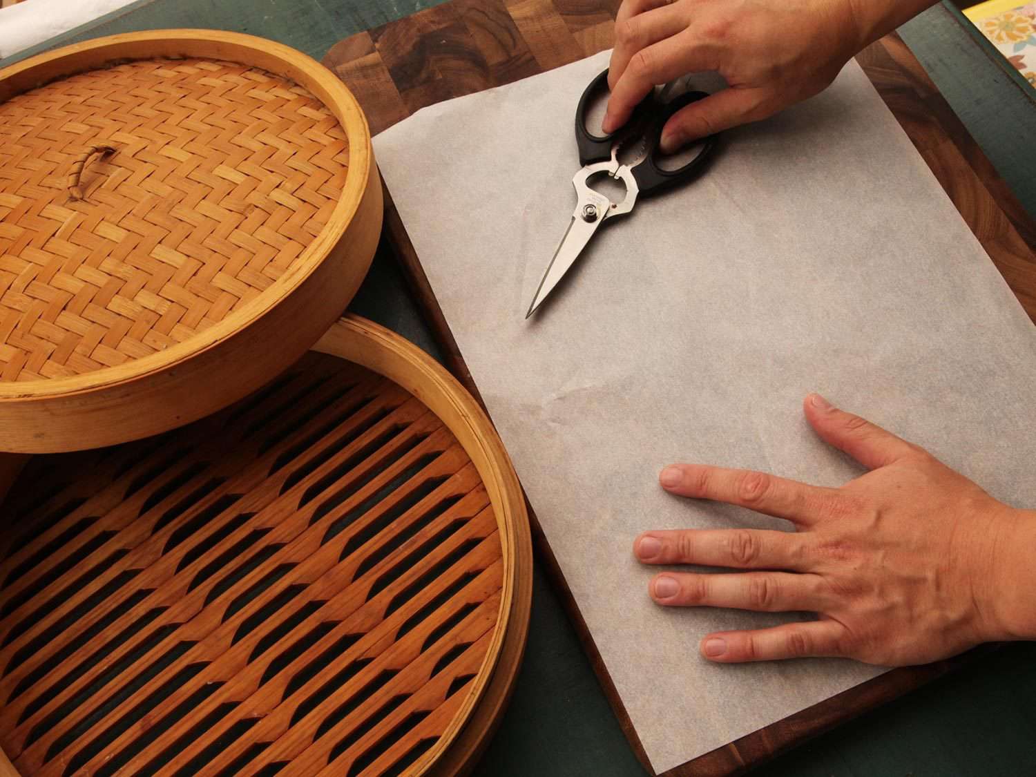 Cutting parchment paper to line a bamboo steamer basket to prevent dumplings from sticking.