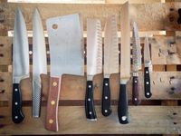 An assortment of knives on a magnetic strip, attached to a wooden pallet