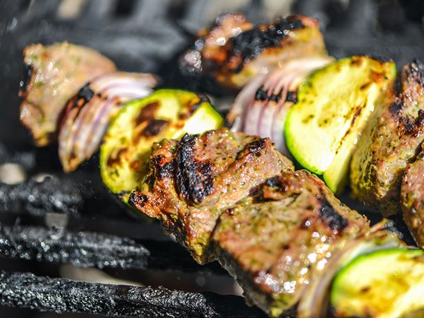 Closeup of two skewers getting lightly charred on the grill.