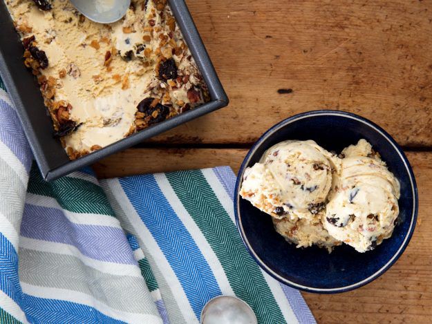 Overhead of two scoops of homemade oatmeal cookie ice cream in a bowl next to a tea towel.