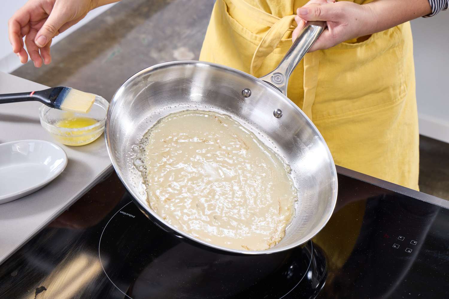 A person makes a crepe in the Le Creuset 12 Inch Large Tri-Ply Stainless Steel Fry Pan