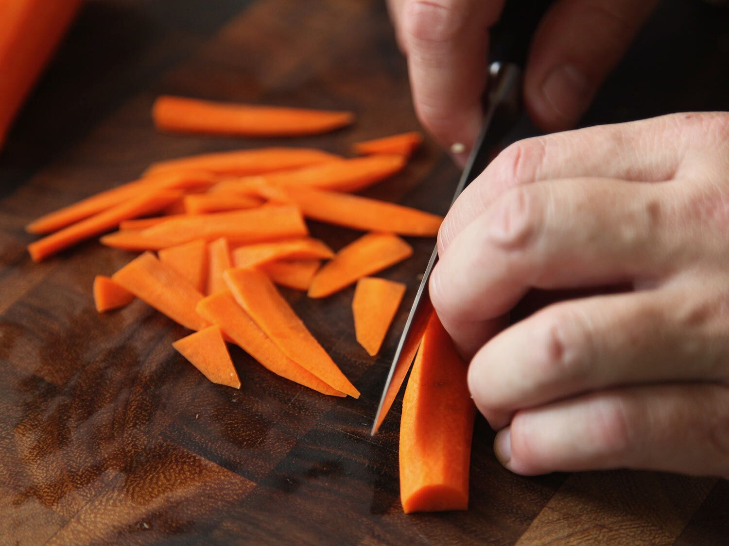 Thinly slicing carrots on a cutting board for bibimbap