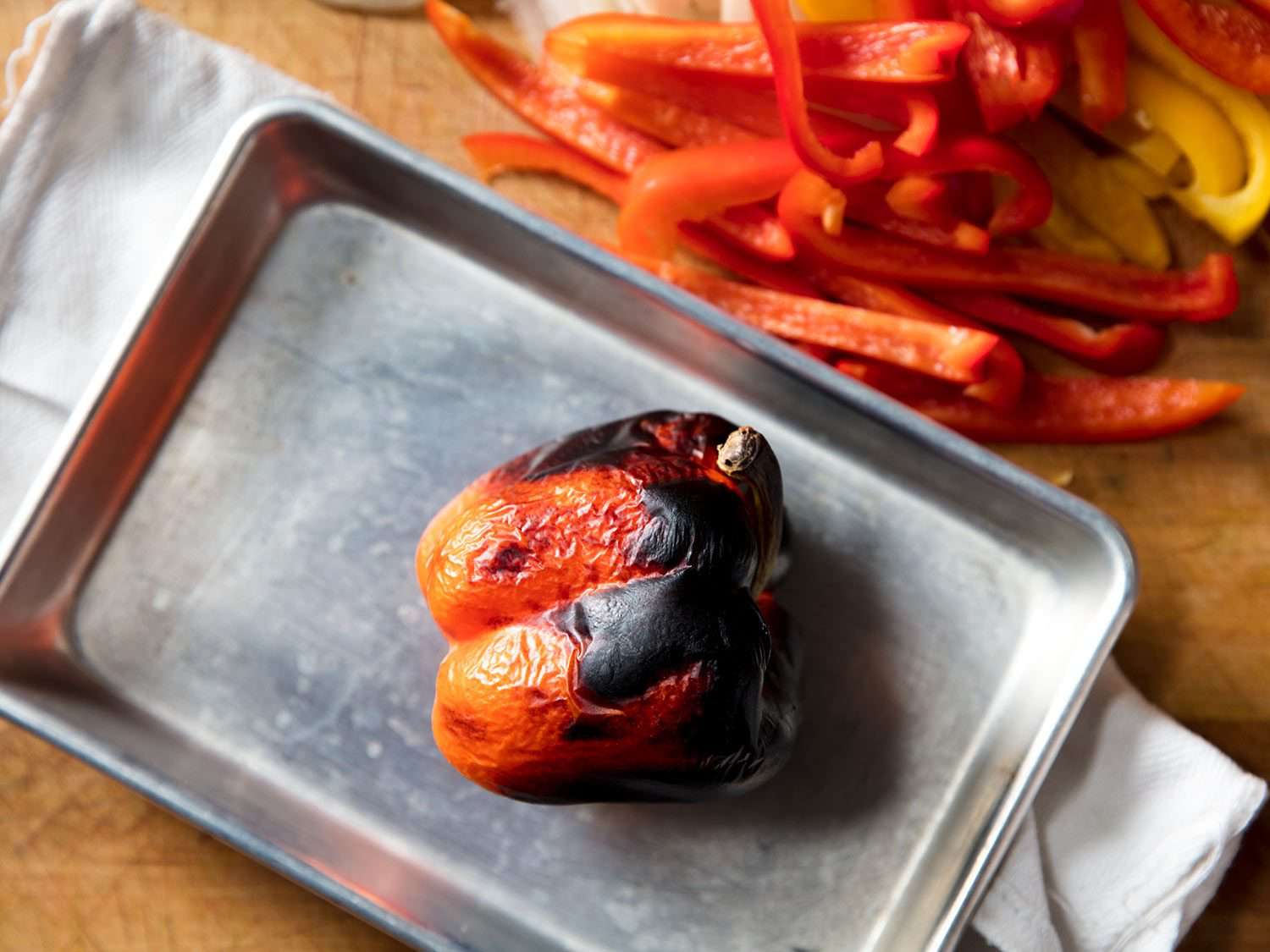 An eight-sheet pan with a roasted red bell pepper on it.