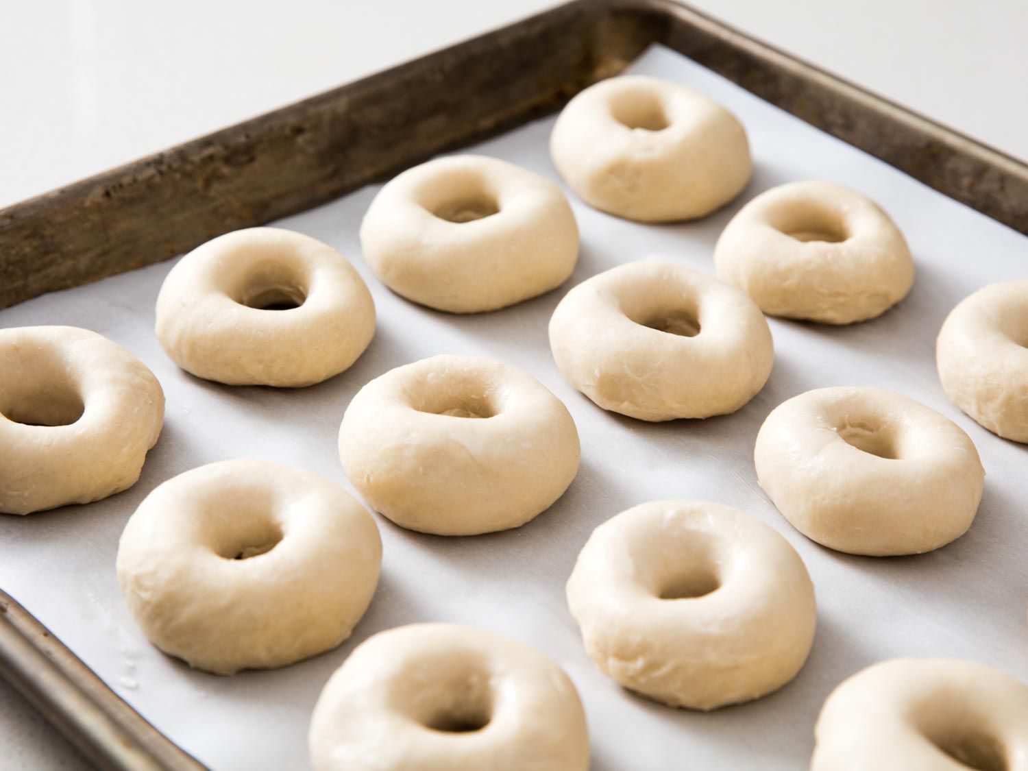 Formed mini bagels on a parchment-lined baking sheet.