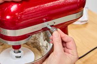 A person locks the head on the KitchenAid Artisan Mini 3.5-Quart Tilt-Head Stand Mixer