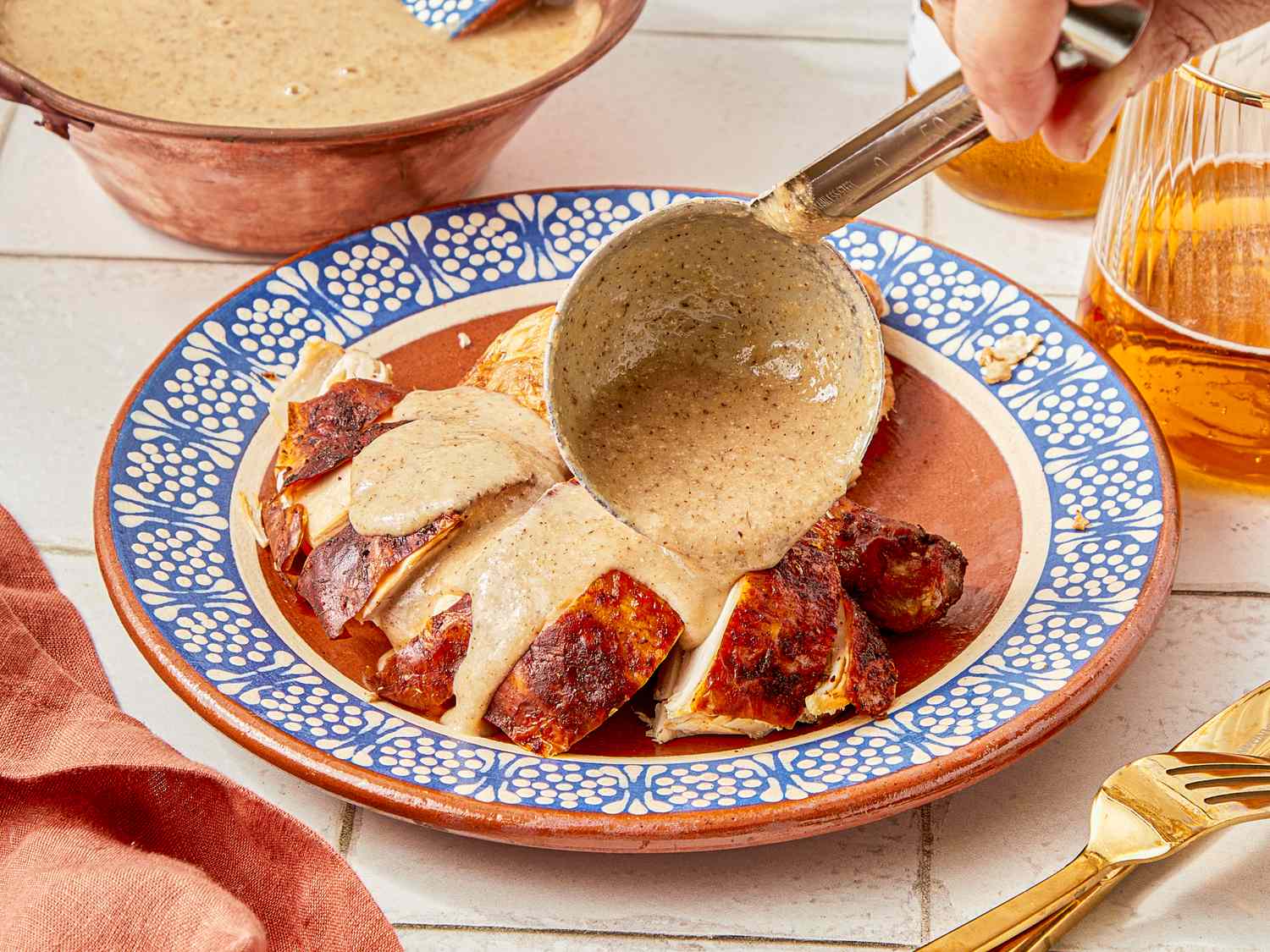 Serving mole blanco sauce over sliced chicken on a decorative plate