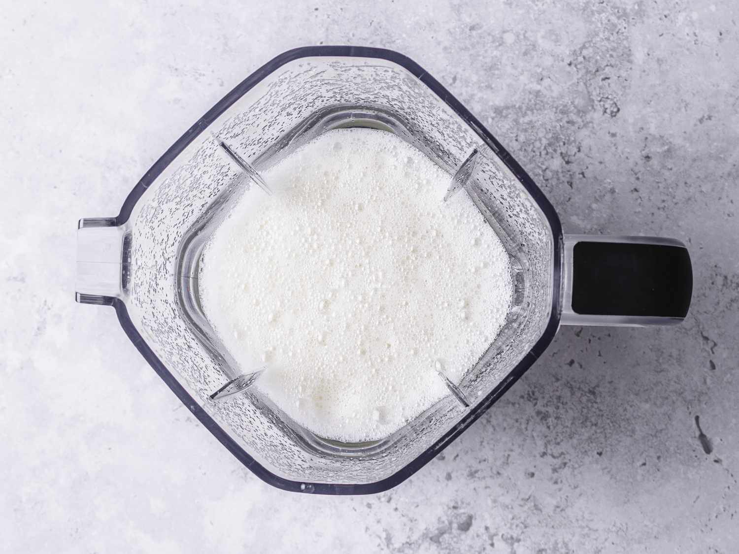 Overhead view of garlic, ginger, and water mixed together in a blender