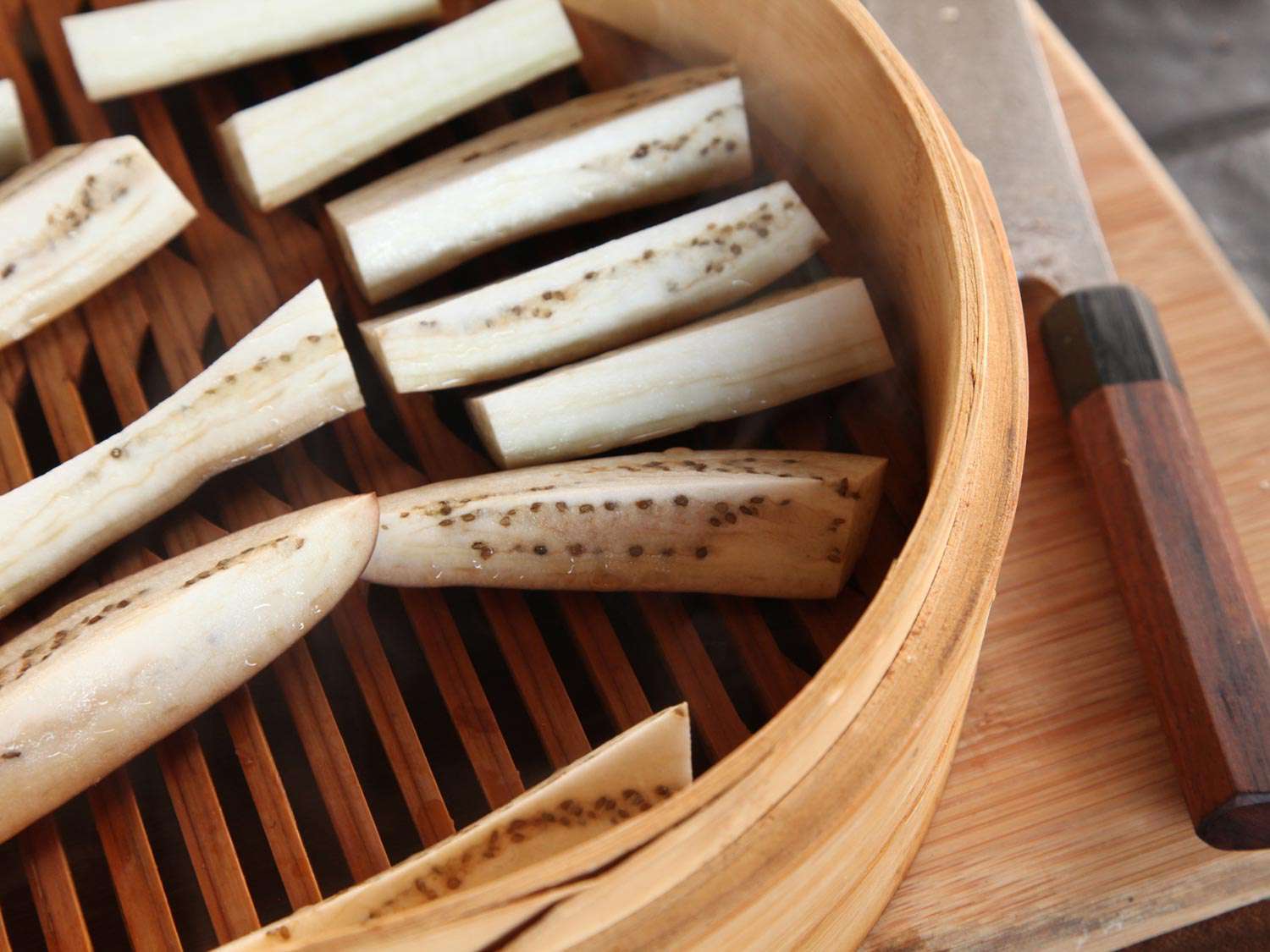 Quartered lengths of Chinese eggplant arranged in a bamboo steamer.
