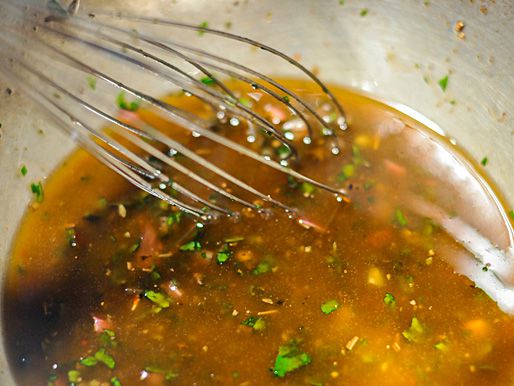 The dressing ingredients are whisked together in a mixing bowl.