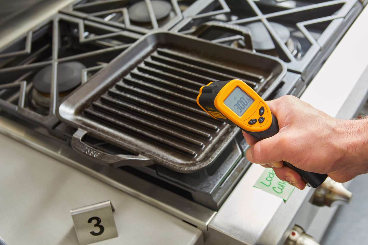 A person measuring the temperature of the Lodge 11-Inch Cast Iron Square Grill Pan