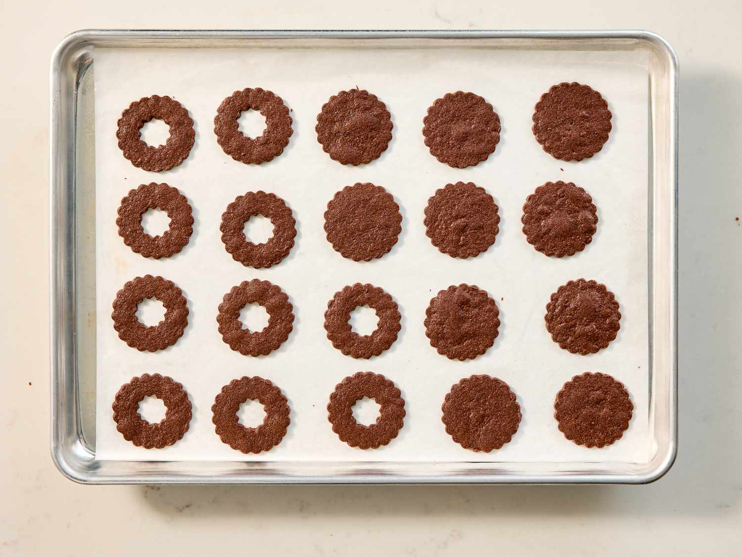 Tray of baked chocolate cookies in rows some with holes in the center