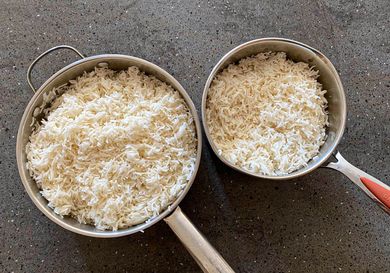 Two pots filled with cooked rice one large and one smaller placed on a dark surface