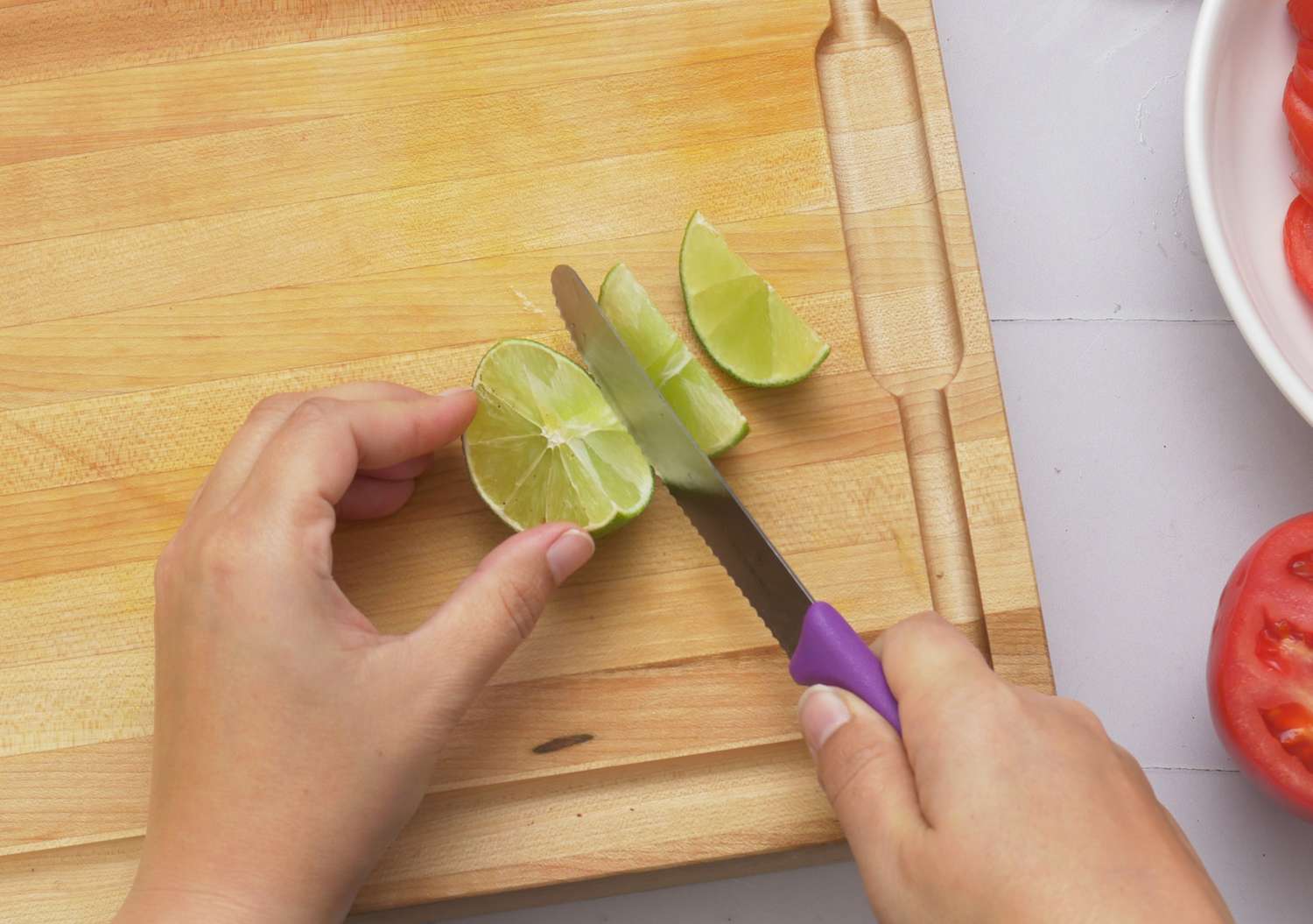 a person slicing a lime into wedges
