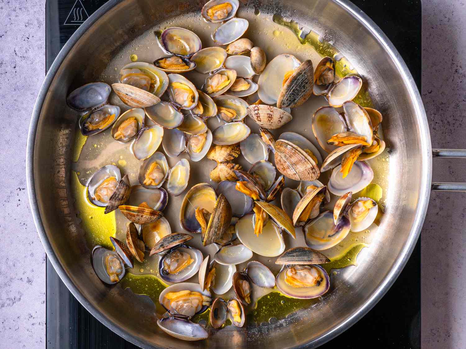Clams being cooked in a pan with oil