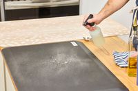 A person sprays the GelPro NewLife Bio-Foam Professional Anti-Fatigue Mat with cleaning solution