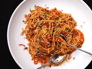 Overhead view of pasta with crab, tomato, and chiles, served in a large white bowl.