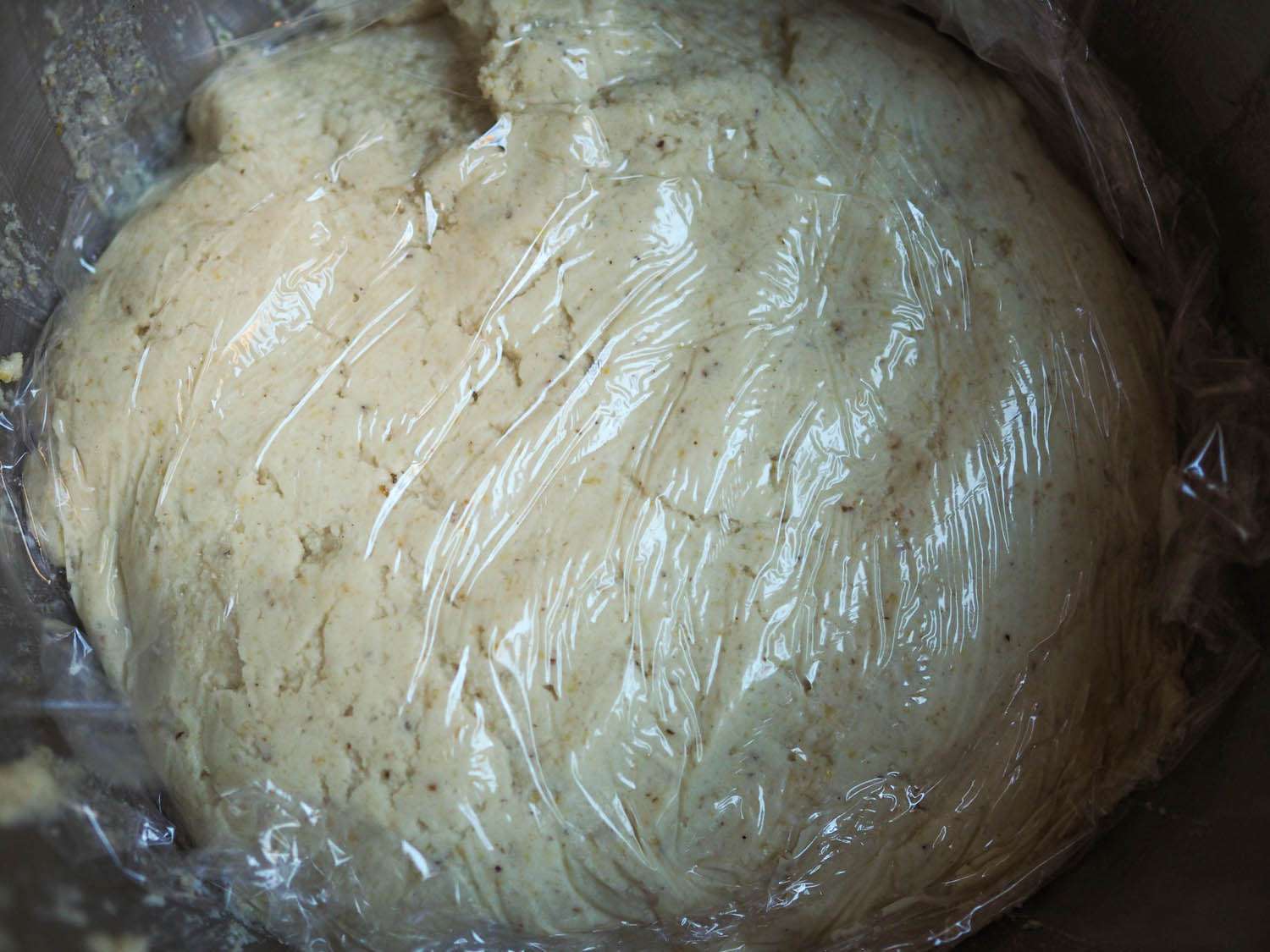 Plastic wrap is pressed against the surface of the masa dough.